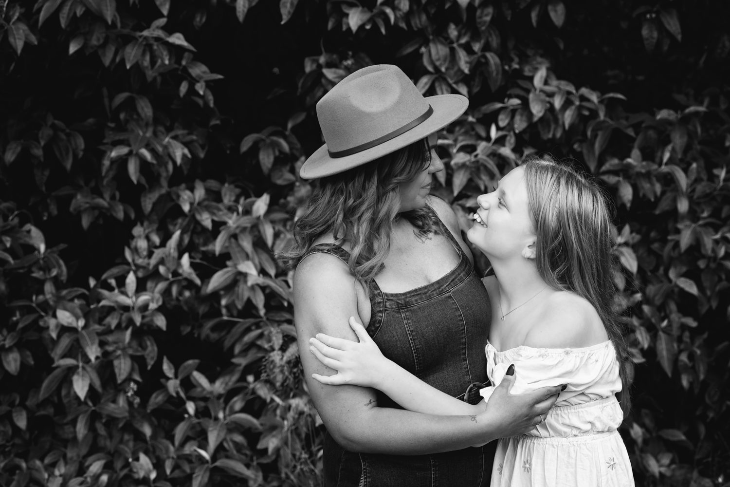 Black and white photo mum and daughter hugging, smiling and looking at eachother.