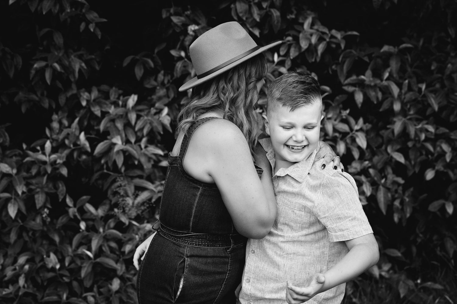 Black and white photo mum and eldest son hugging, laughing.