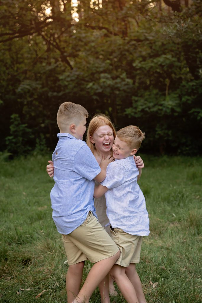 Family photography session. three siblings laughing and tickling each other. standing
