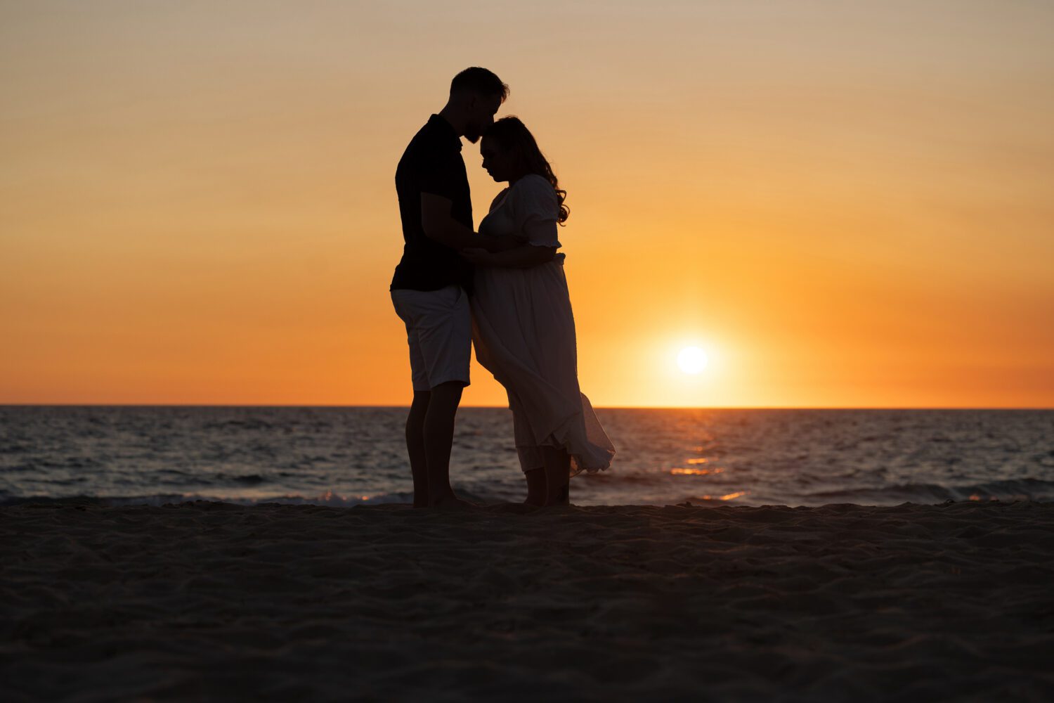 Expectant couple sharing a tender moment on Scarborough Beach bathed in warm golden sunset light — maternity photography by Aurora Joy Photography, Scarborough Western Australia

Perth maternity photographer