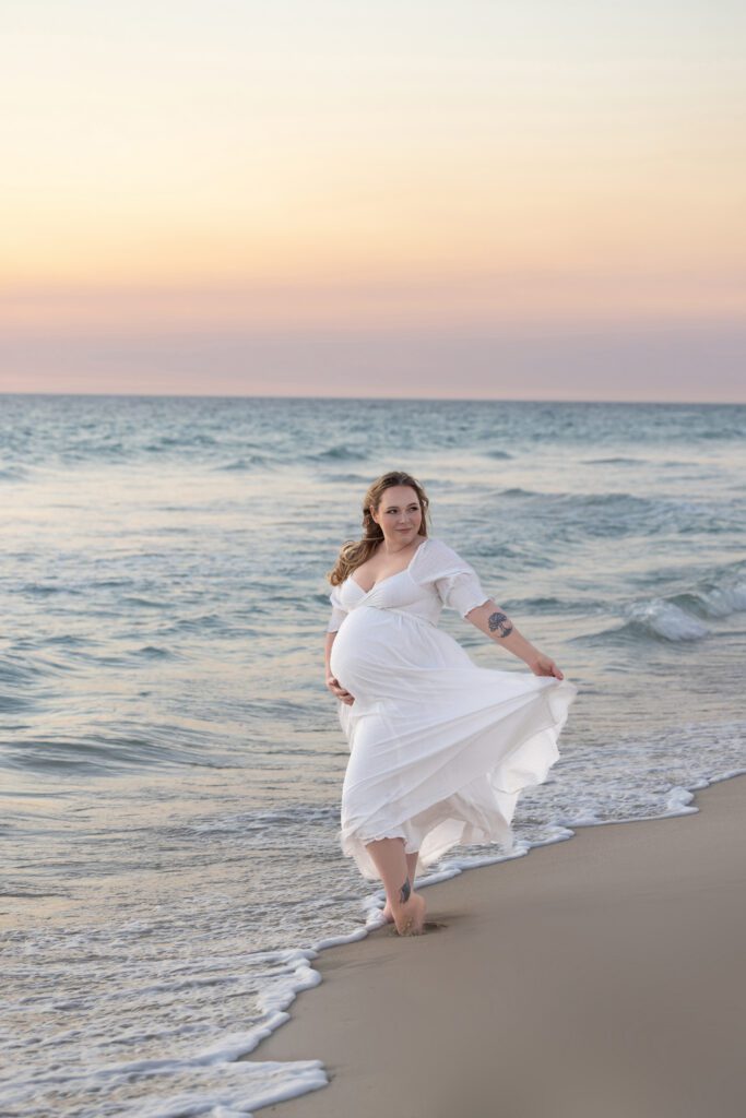 Expectant mother elegantly draped in soft white fabric in a side profile pose, showcasing her baby bump — maternity photography by Aurora Joy Photography, Scarborough Western Australia