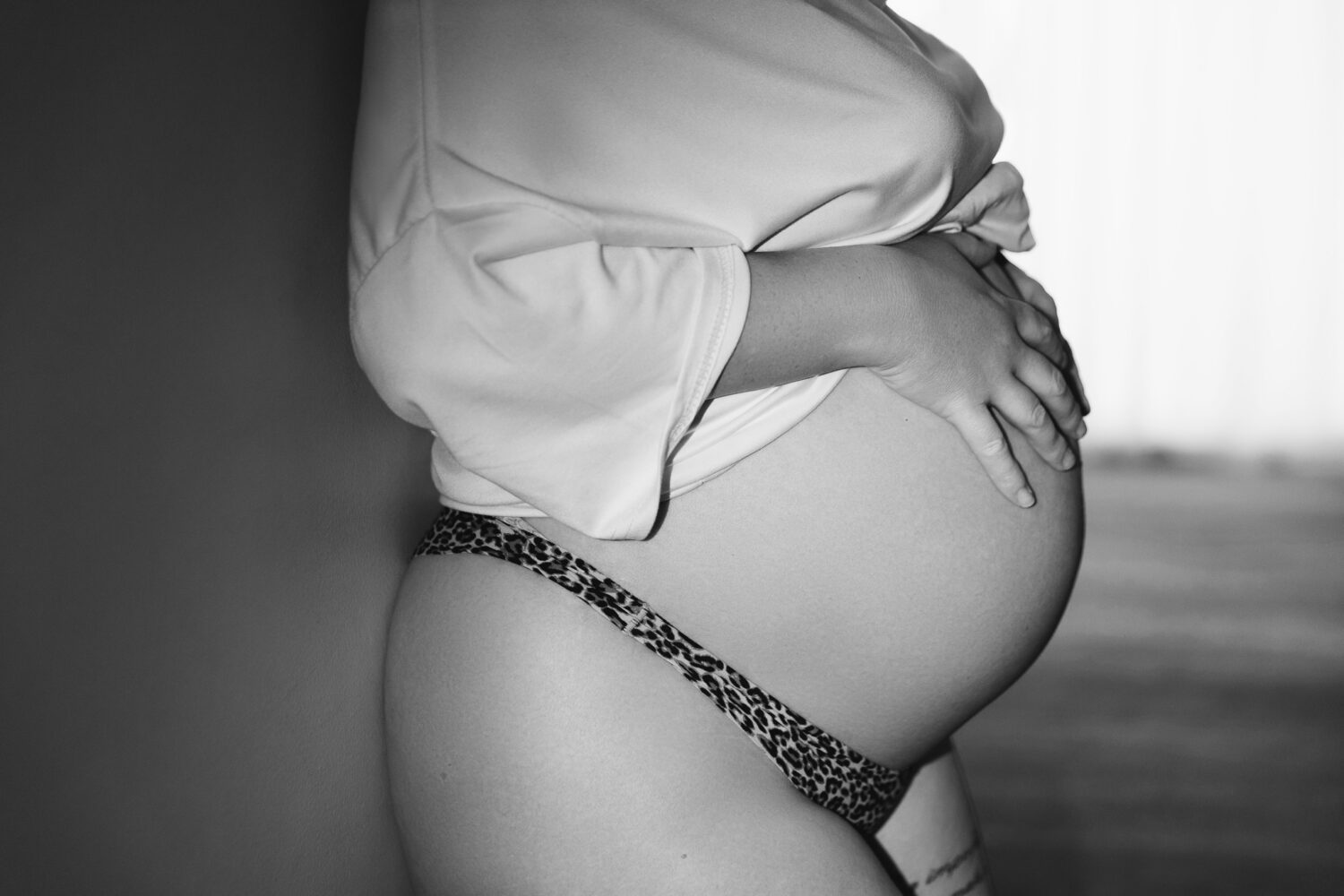 Black and white close-up side profile of a pregnant woman's bare baby bump— maternity photography by Aurora Joy Photography, Scarborough Western Australia