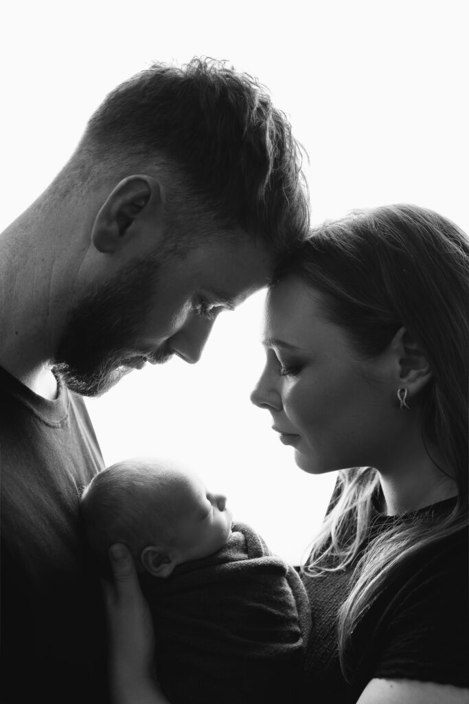 Black and white intimate studio portrait of both parents with their newborn baby boy — newborn photography by Aurora Joy Photography, Stirling Western Australia