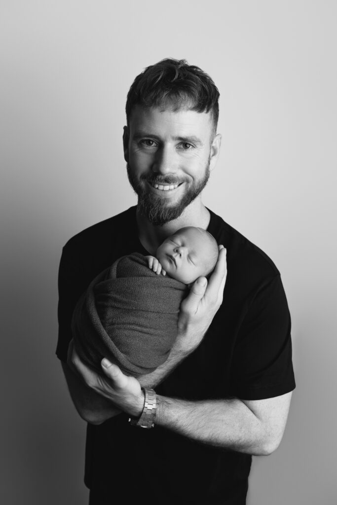 newborn photographer Perth Black and white intimate studio portrait of father with their newborn baby boy — newborn photography by Aurora Joy Photography, Stirling Western Australia